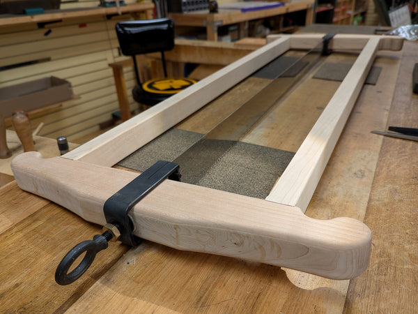 Wooden frame with a rectangular opening on a wooden surface, likely in a workshop setting.