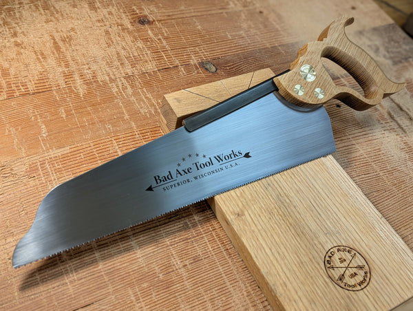 a 14 inch half back saw with a white oak handle made by bad axe tool works
